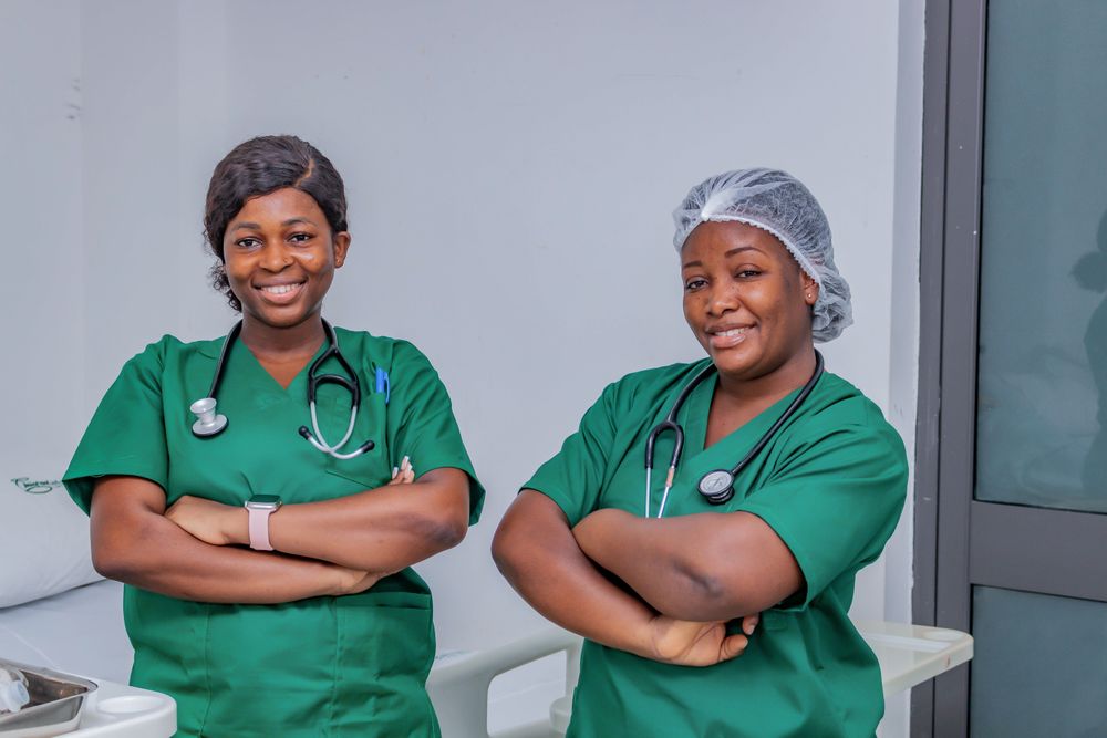 Two nurses in green scrubs smiling together